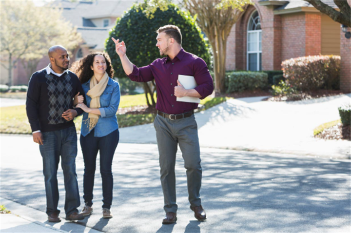 Real estate contractor walking with homeowners touring residential neighborhood to discuss project requirements
