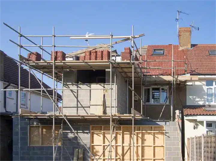 Residential home extension construction site with scaffolding, house renovation building project