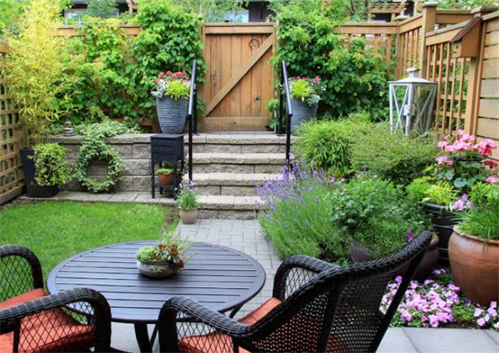 Cool stone paver backyard patio with wicker seating, layered native plant landscaping and privacy fencing