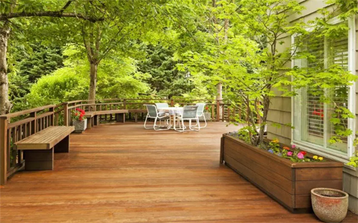 Large shaded hardwood residential deck with patio furniture, built-in benches and planters, cool outdoor living space