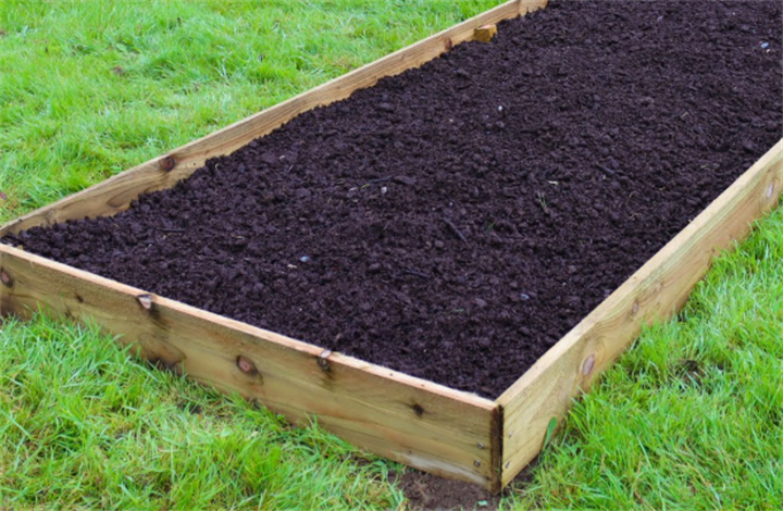 Simple wooden raised bed filled with loose nutrient-rich soil, perfect alternative to digging on solid New England bedrock terrain