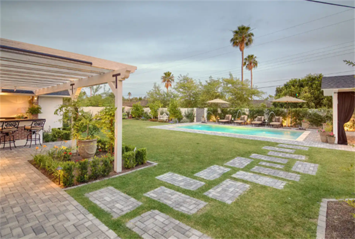 Spacious Phoenix residential backyard with pergola, lawn, swimming pool and cooling hardscape layout