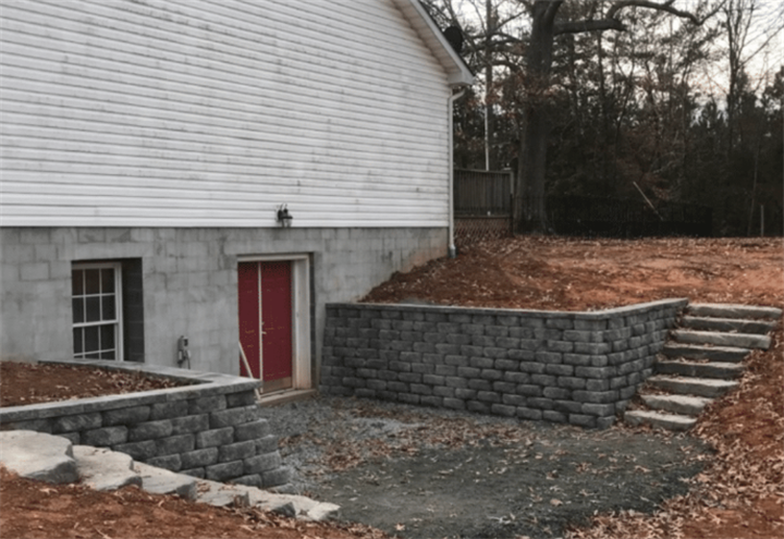 Curved concrete block retaining wall around home basement entrance for Minnesota frost protection
