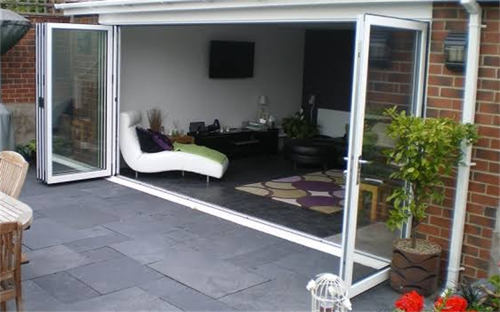 White aluminium folding glass doors opening living room out to outdoor patio space
