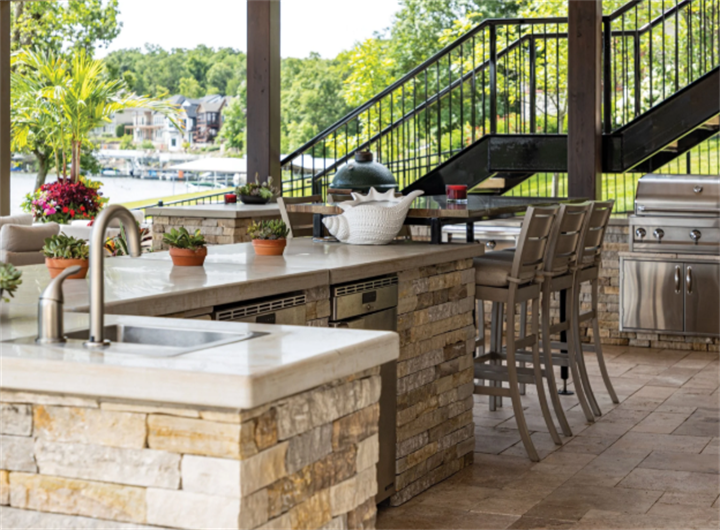 Stacked stone outdoor kitchen bar with sink built to stabilize uneven lakeside slope