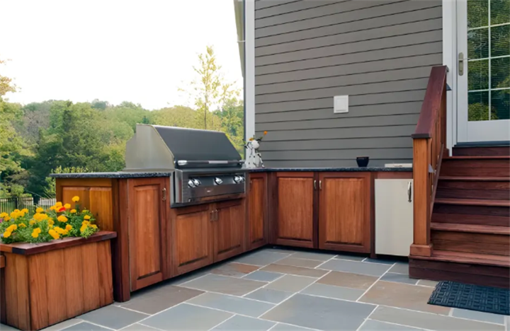 Dark wood outdoor grill station built on tiered flagstone patio sloped backyard
