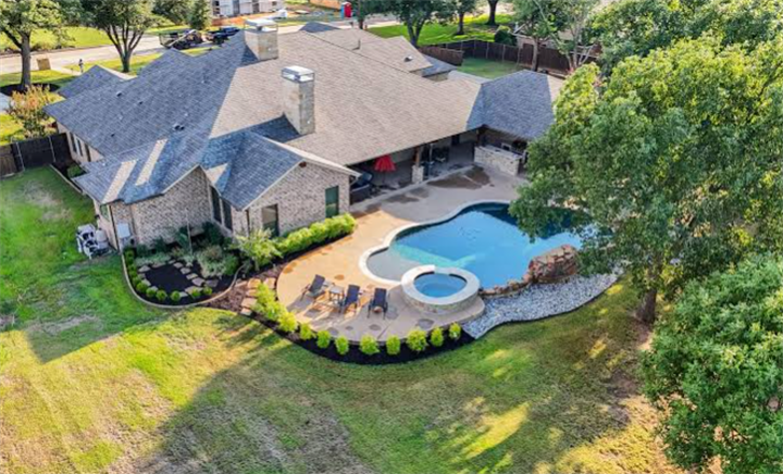 Overhead shot of small residential backyard with swimming pool, patio lounge area, and landscaped green space