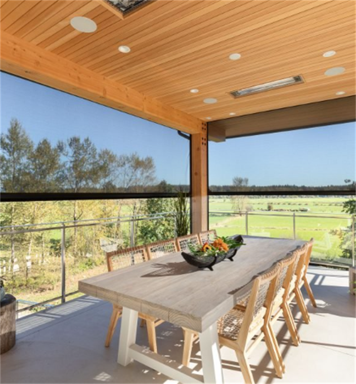 Wood-ceiling covered dining porch enclosed by large insect mesh screens with panoramic countryside views