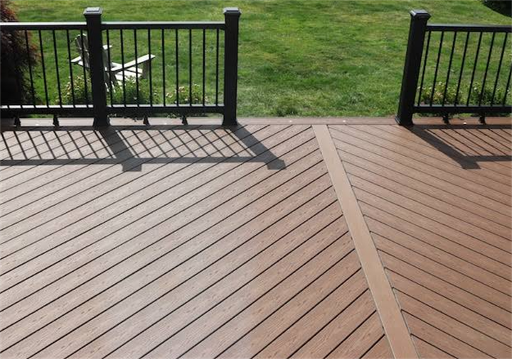 Composite deck with diagonal plank layout and contrasting border, black metal railing to avoid plain linear flooring