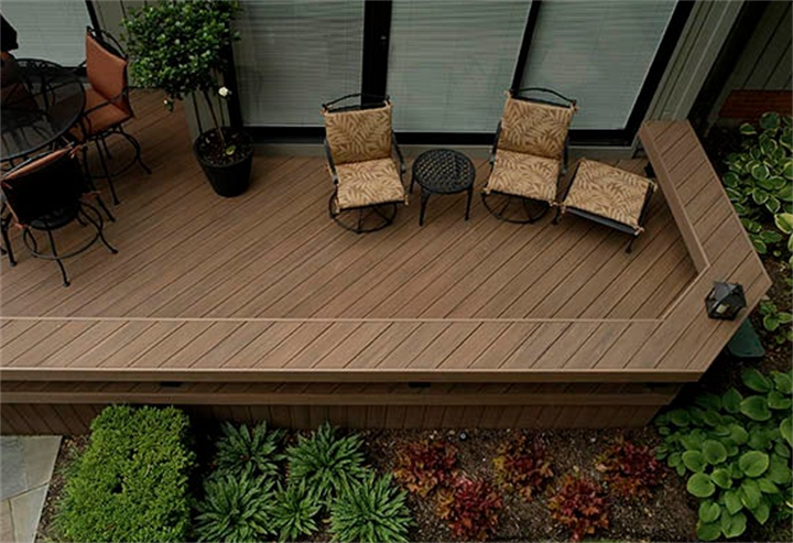 Overhead view of raised backyard deck with straight parallel boards contrasted against angled perimeter deck framing